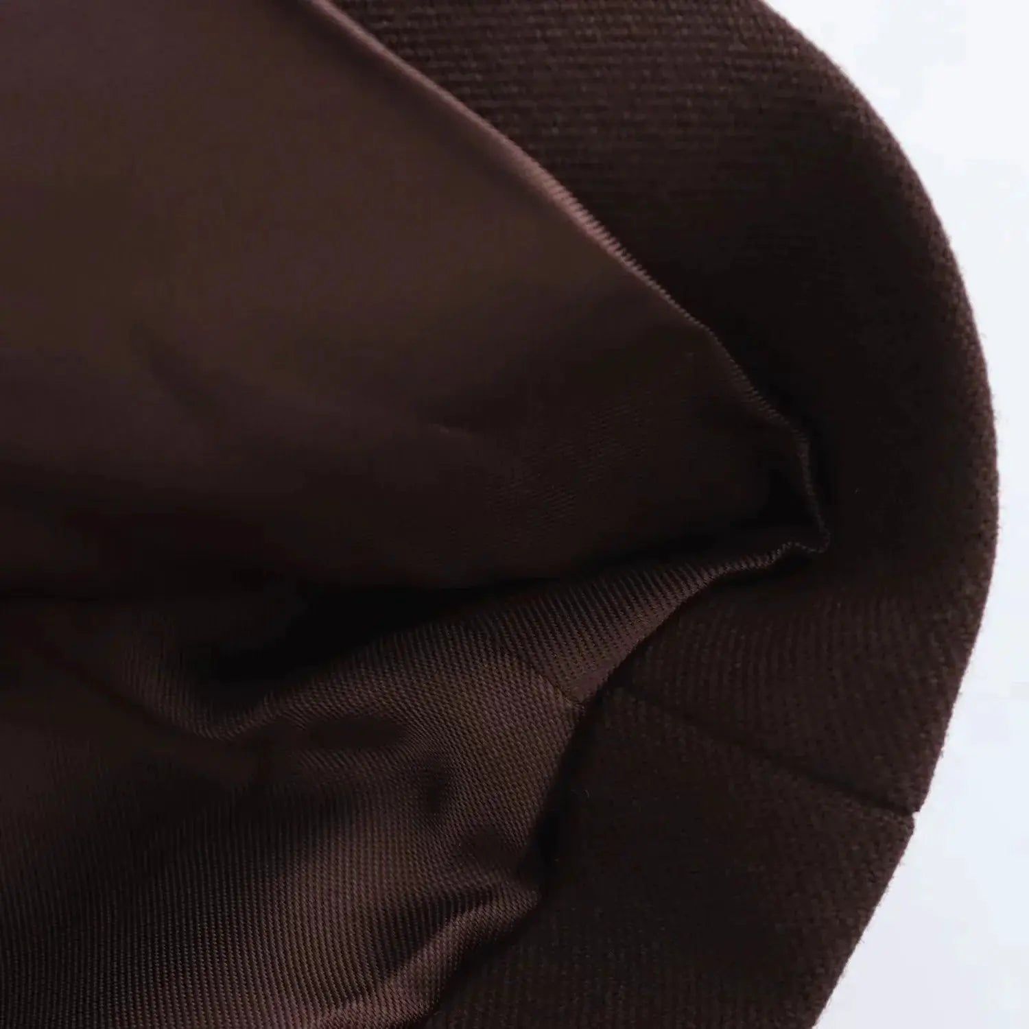 Brown blazer fabric close-up with visible seam and zipper edge.