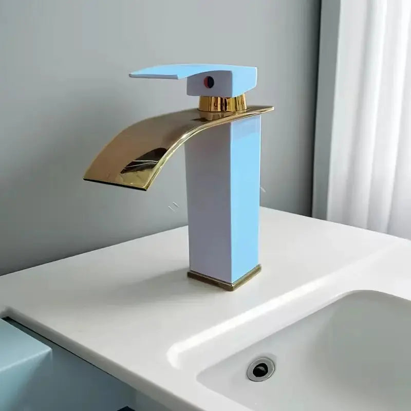 Waterfall wash basin faucet in blue with gold spout and column mounted on a white sink