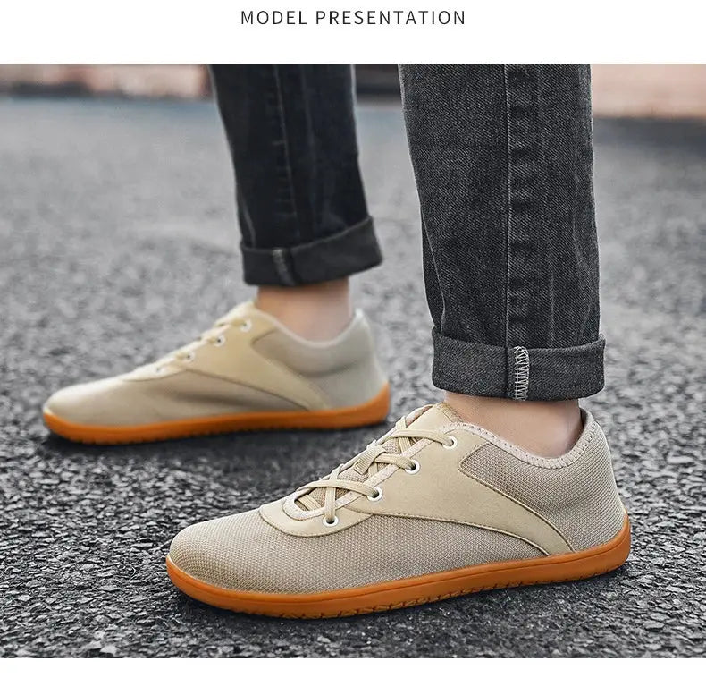 Minimalist beige trail running shoes pair with orange sole on asphalt