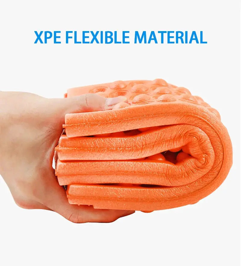 Camping foam pad orange, rolled up in hand for easy transport