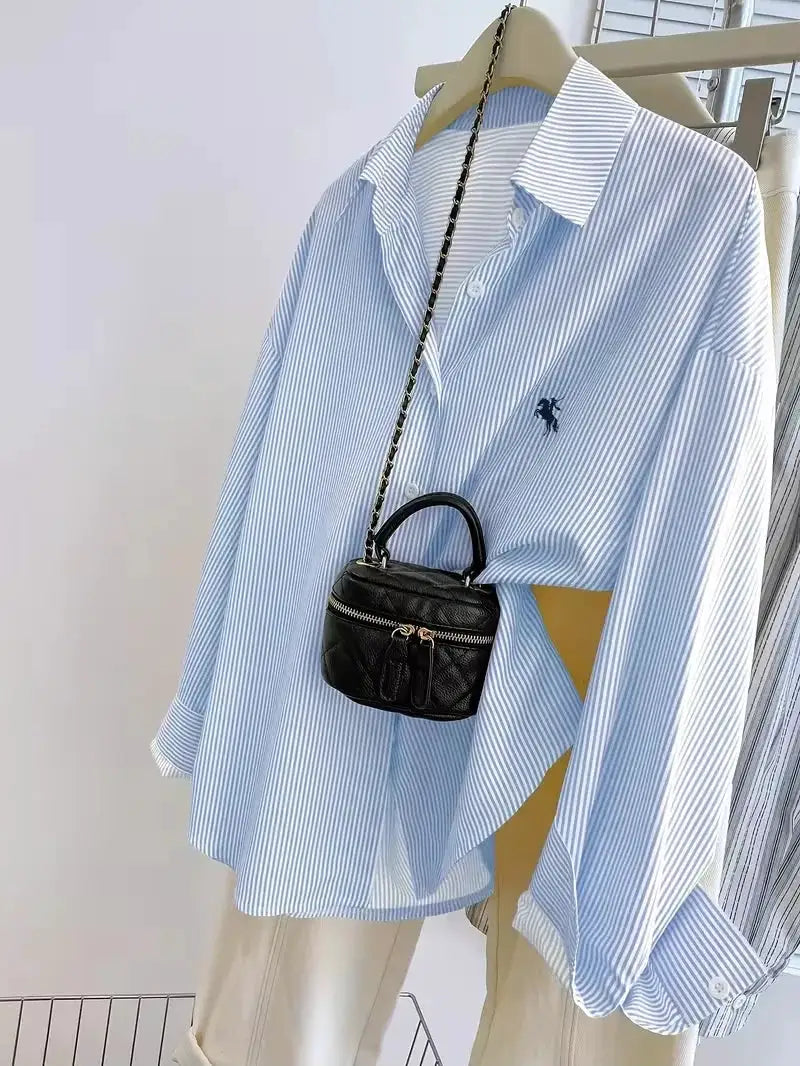 Women's long-sleeve light-blue striped button-up blouse with a small knight logo on the chest.