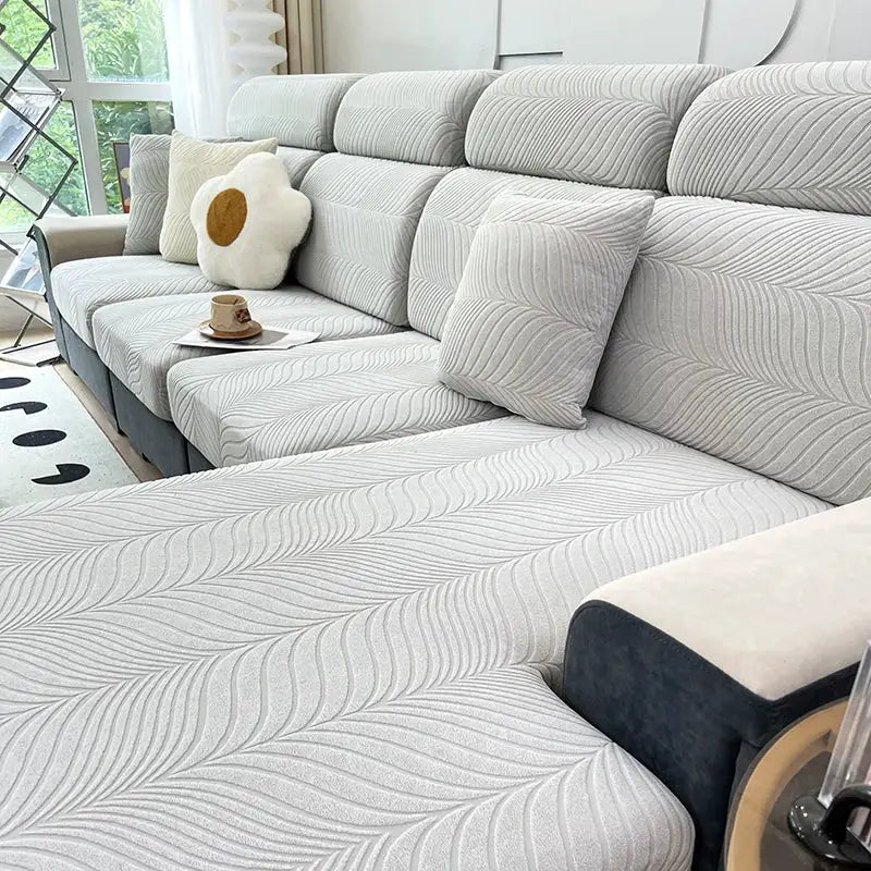 Splash-proof jacquard sofa cover on a grey sectional couch; high-elastic, anti-dirt and anti-scratch cushions