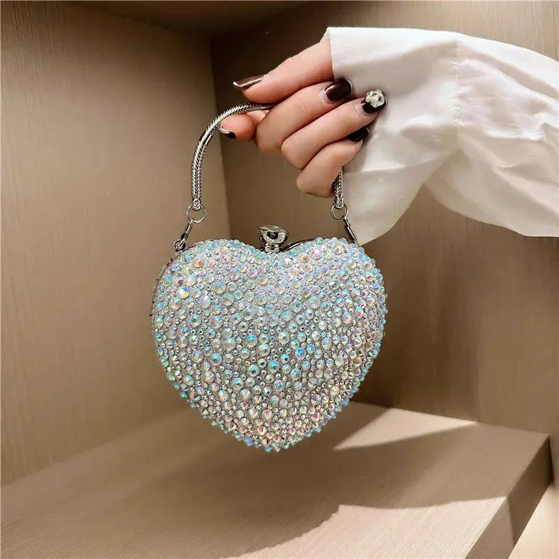 Heart-shaped crystal clutch purse covered in iridescent rhinestones with a silver chain handle for evening wear.