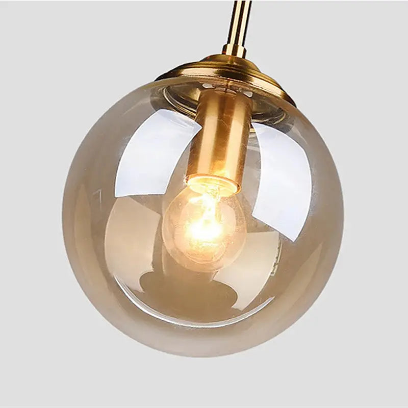 Modern glass globe pendant lamp with gold metal hardware and visible LED bulb