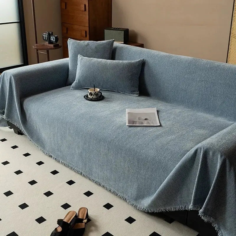 Chenille sofa cover with tassel fringe in blue-gray, draped over a living room sofa