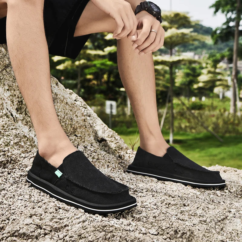 Men's black canvas slip-on loafers with white sole, breathable low-top casual shoes; two pairs shown.