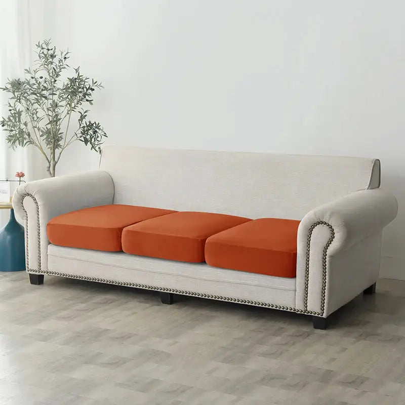 Plush beige sofa slipcover with three orange cushions; anti-slip elastic couch cover for living room furniture