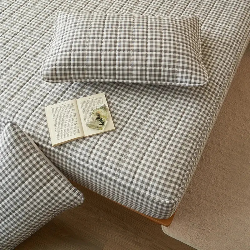 Quilted plaid mattress protector in gray-and-white checks with two matching pillows