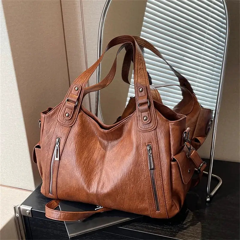 Shoulder bag in brown PU leather with dual top handles, front zip pockets, and detachable crossbody strap
