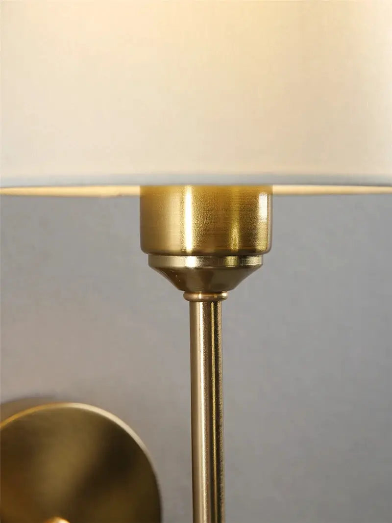 Wall sconce lamp with brass finish and beige cloth shade