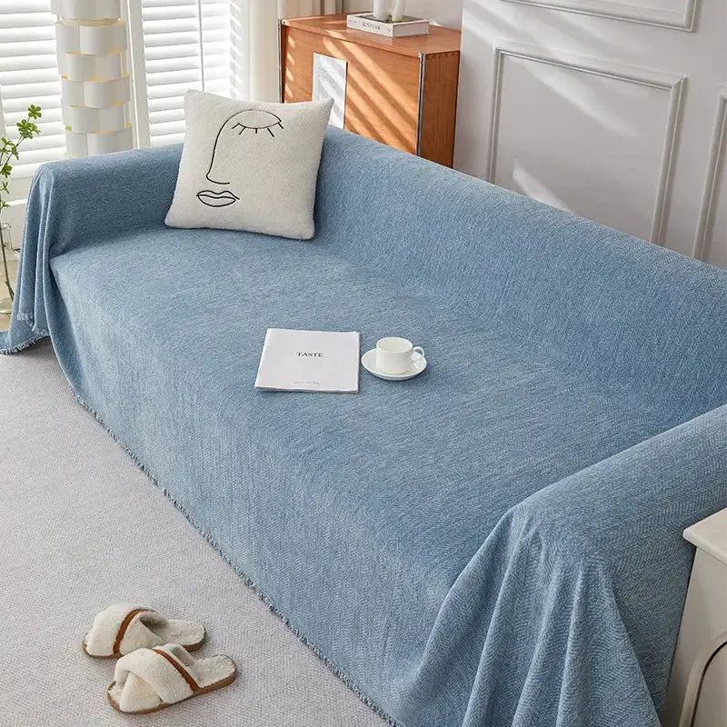 Couch cover by Simples Market in blue chenille with fringe and herringbone texture; decorative pillow and cup on sofa