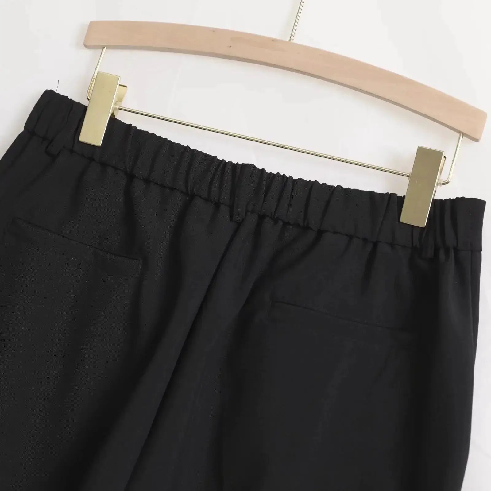 Men's black baggy casual pants with elastic waistband, hanging on a wooden hanger