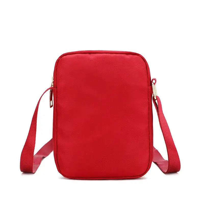 Women's red waterproof crossbody bag with adjustable strap and gold hardware