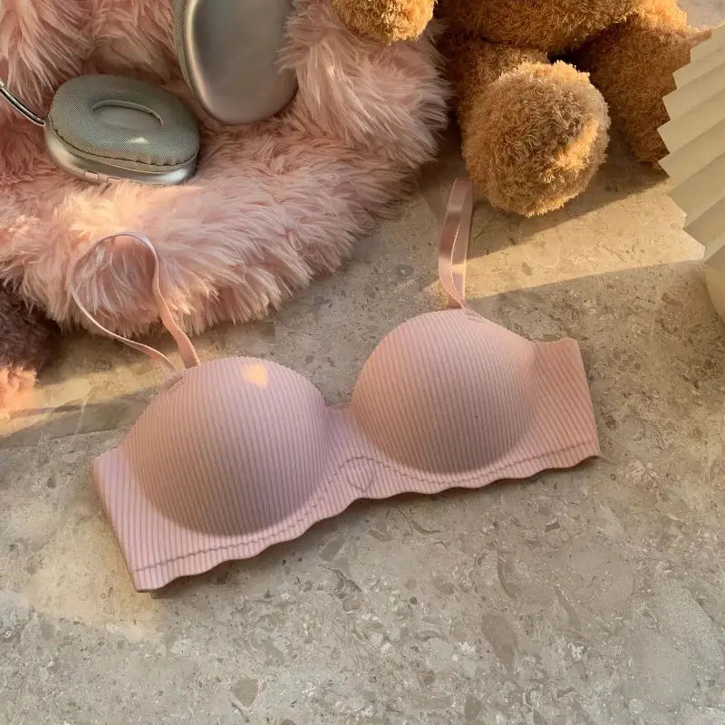 Pink ribbed seamless push-up bra with adjustable straps on a pink fluffy background.