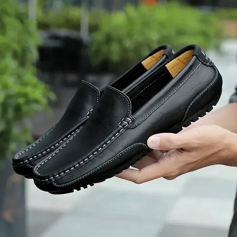 Pair of men's black leather loafers; slip-on moccasins with white stitching