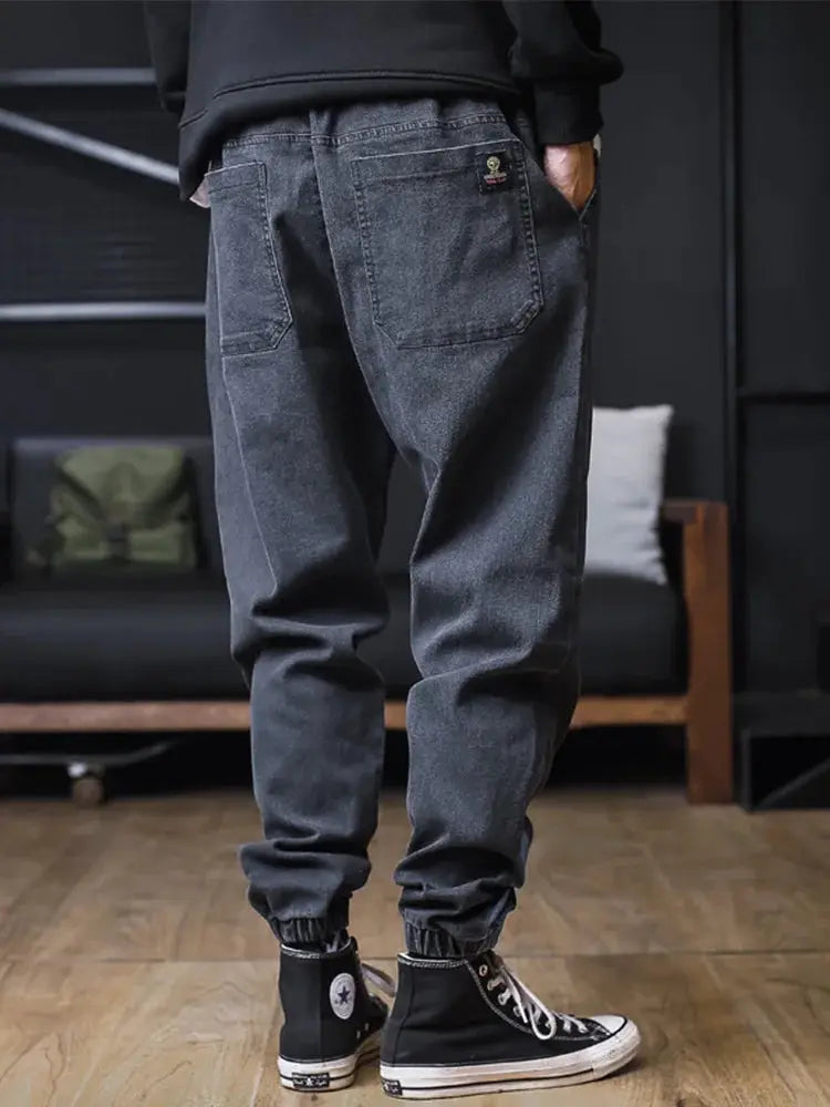 Plus-size men's denim jogger jeans, loose fit with back pockets and elastic ankle cuffs.
