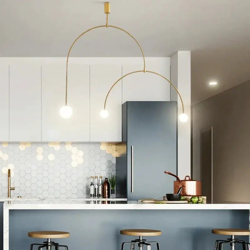 Nordic minimalist chandelier by Simples Market with gold curved arc arms and globe bulbs over a kitchen island