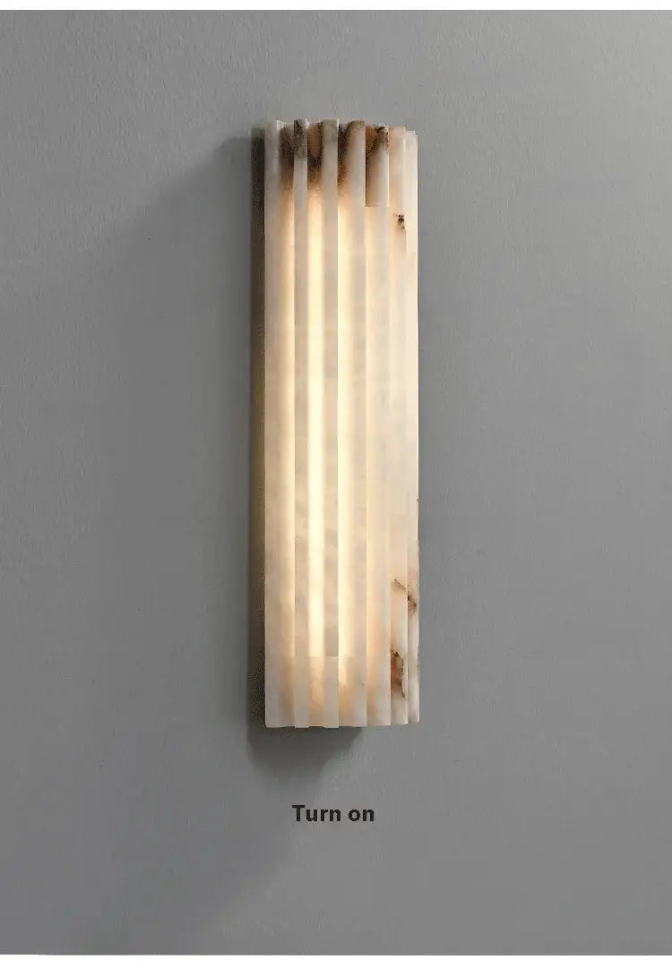 Marble wall lamp by Simples Market; modern minimalist bedside sconce with vertical cream marble slats and warm light.