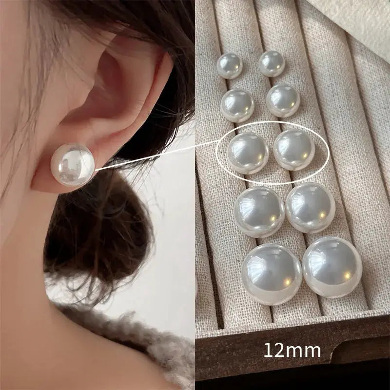 Sterling silver pearl stud earrings, 12mm white-gray pearls; model wearing one on the ear.