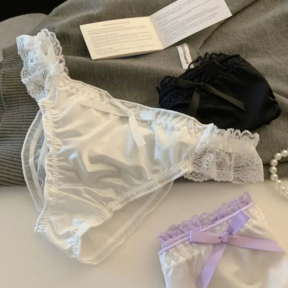 Three women's panties set in white satin lace, black lace, and lavender satin with bows; low-rise briefs.