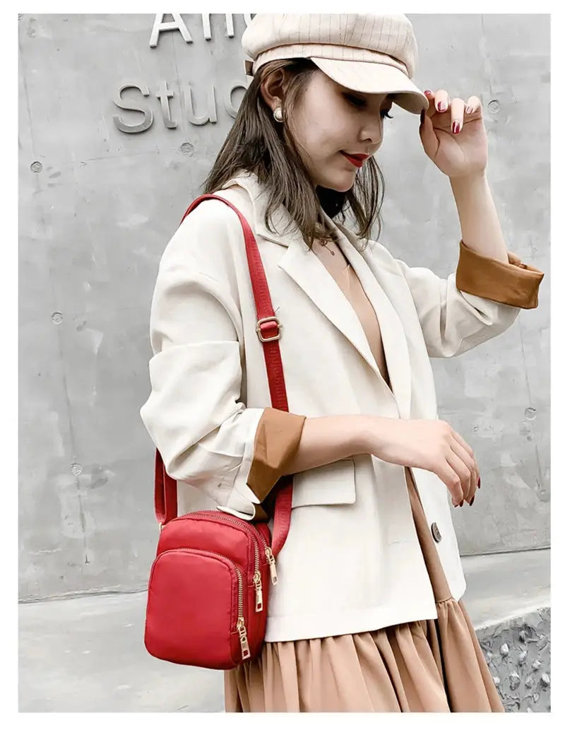 Women's red compact crossbody bag with adjustable strap and gold zippers