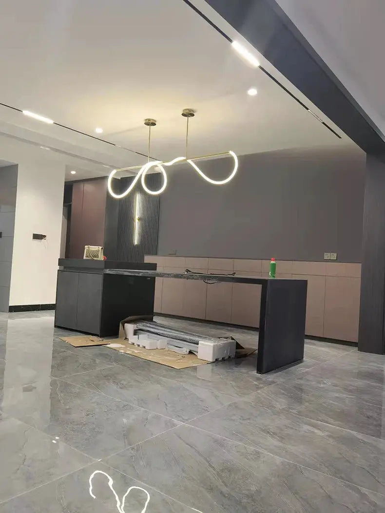 Nordic LED pendant chandelier with dual gold-tone looping rings over a modern kitchen island