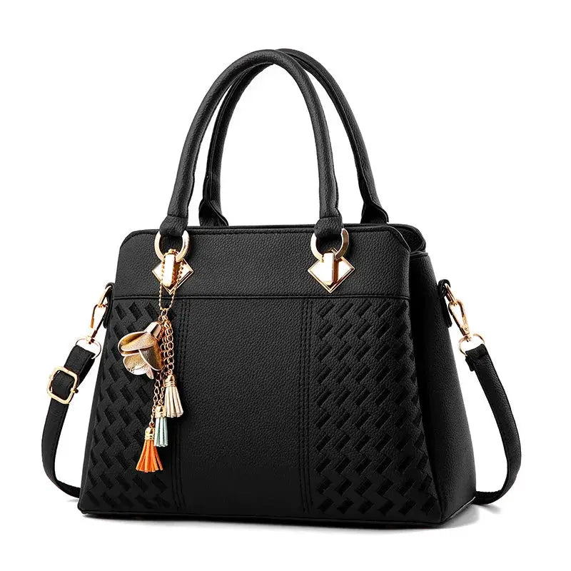 Women’s black PU leather handbag by Simples Market with top handles and tassel charms, crossbody strap