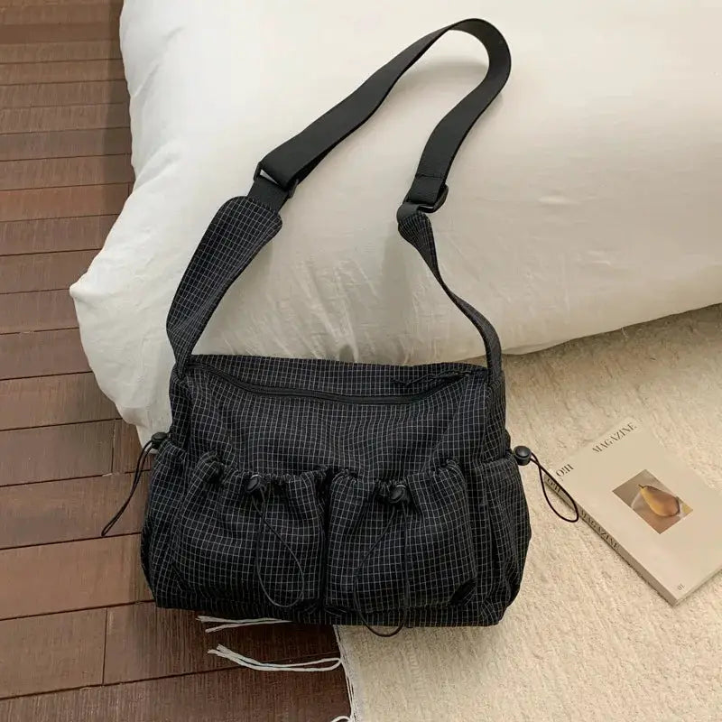 Simples Market nylon plaid shoulder bag with front drawstring pockets, black crossbody style.