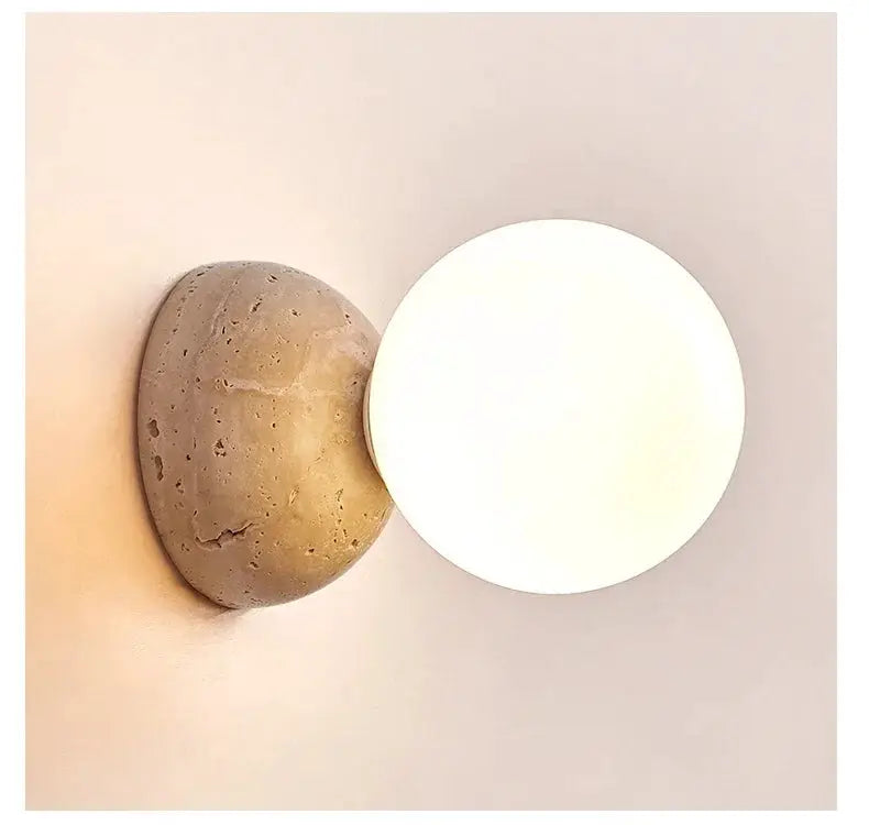 Cream-style LED wall lamp with round white diffuser on a stone backplate