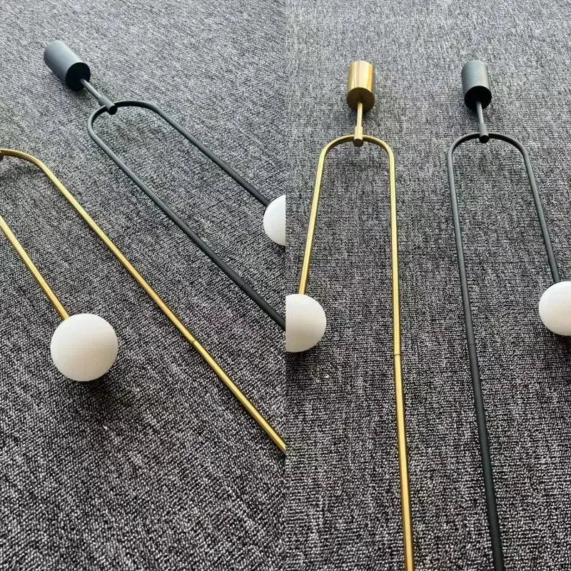 Set of three modern glass ball pendant lights by Simples Market; gold and black metal frames with white glass spheres.