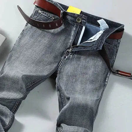 Men's denim jeans, blue gray wash with brown leather belt, straight fit.
