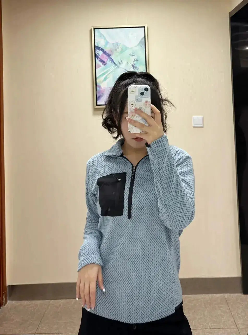 Light blue fleece pullover with wavy pattern, half-zip front and black chest pocket, long sleeves