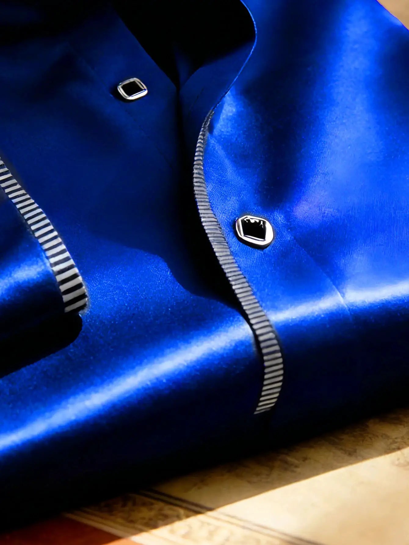 Men's blue satin tuxedo shirt close-up with silver square studs and striped trim