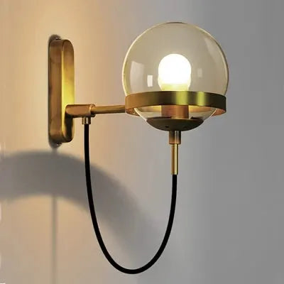 Modern glass globe wall lamp with brass finish and exposed E27 bulb, wall-mounted.