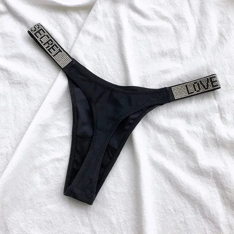 Black low-waist thong with rhinestone straps spelling LOVE and REBEL