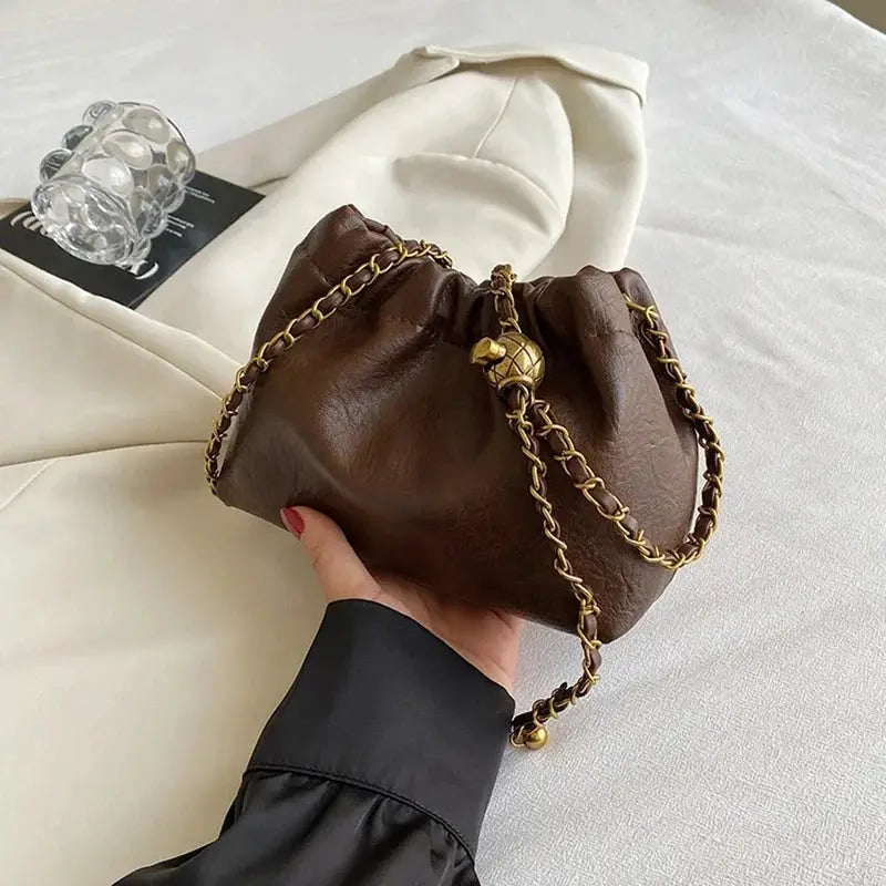 Brown leather chain-strap crossbody bag by Simples Market; compact hobo-style purse with gold-tone hardware