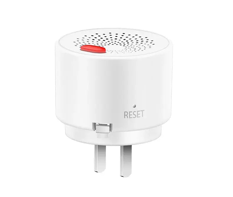 Plug-in gas leak detector with two-prong plug, white circular device with red reset button and vented top.