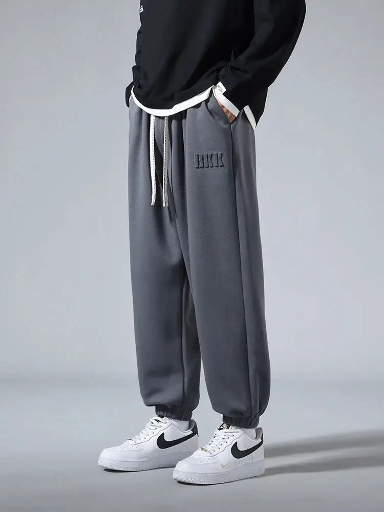 Men's gray cotton-polyester jogger pants with drawstring, cuffed ankles and a logo patch