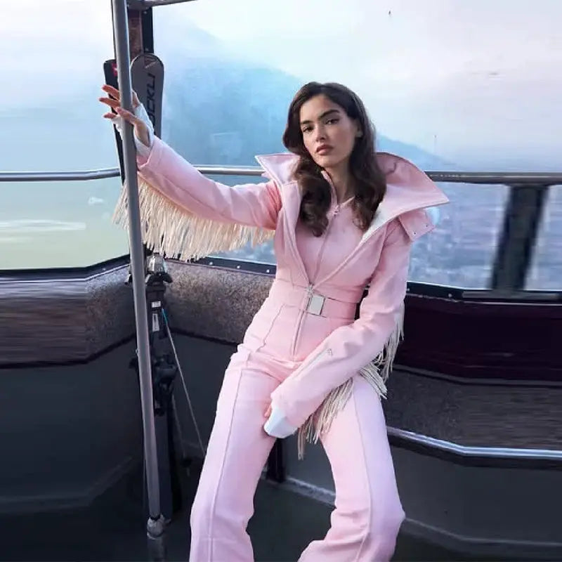 Simples Market pink thickened one-piece ski jumpsuit with faux-fur hood, fringe tassels and high-waist belt.