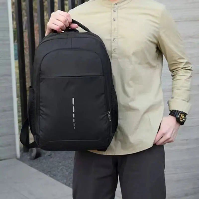 Man holding a sleek black multi-pocket professional laptop backpack outdoors.