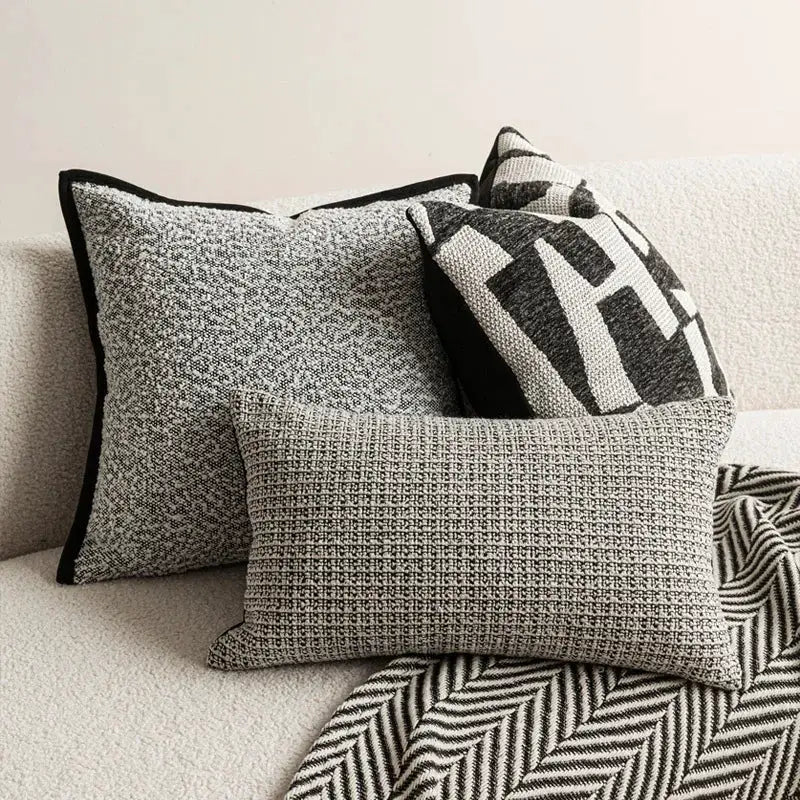 Set of 3 ivory and black decorative pillows with textured and geometric covers for sofa decor.