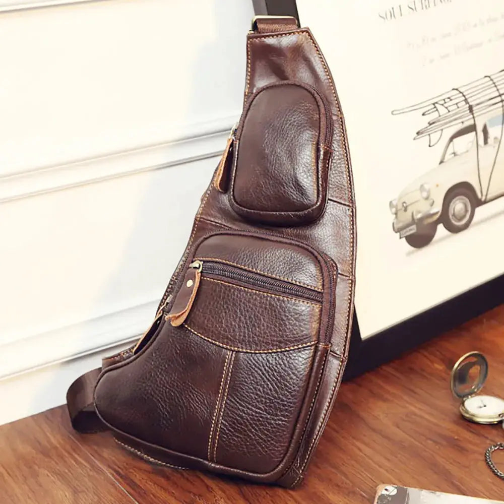 Brown genuine leather men's crossbody sling bag with multiple front pockets and a small zip pouch.