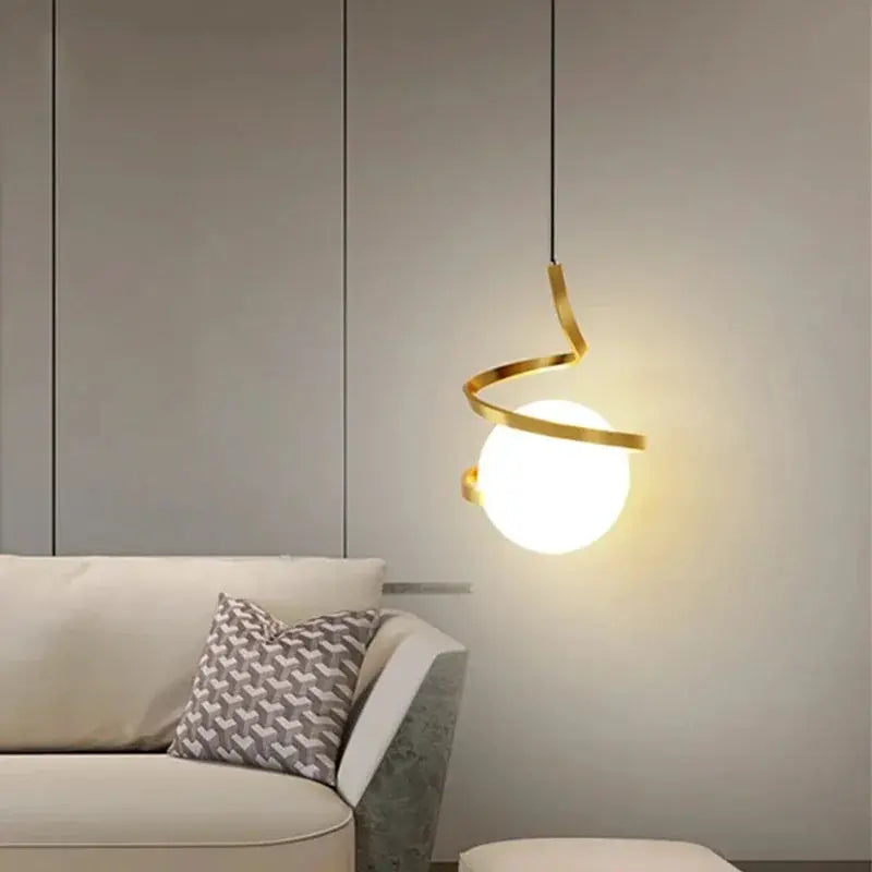 Nordic LED pendant light with gold spiral metal ring and white globe, hanging over a modern living room sofa.