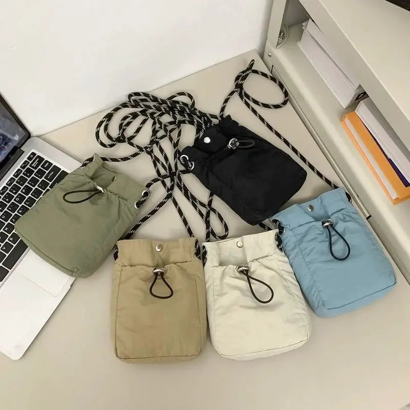 Simples Market nylon crossbody bag set: five soft mini square bags in assorted colors with rope straps.