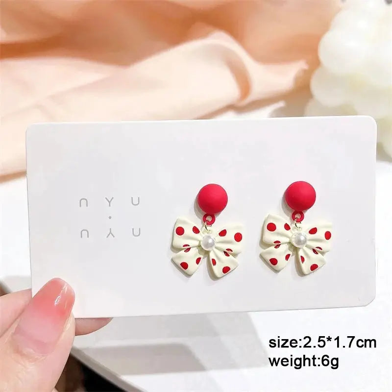 White bow enamel dangle earrings with red polka dots and pearl centers; pair on red studs, Simples Market