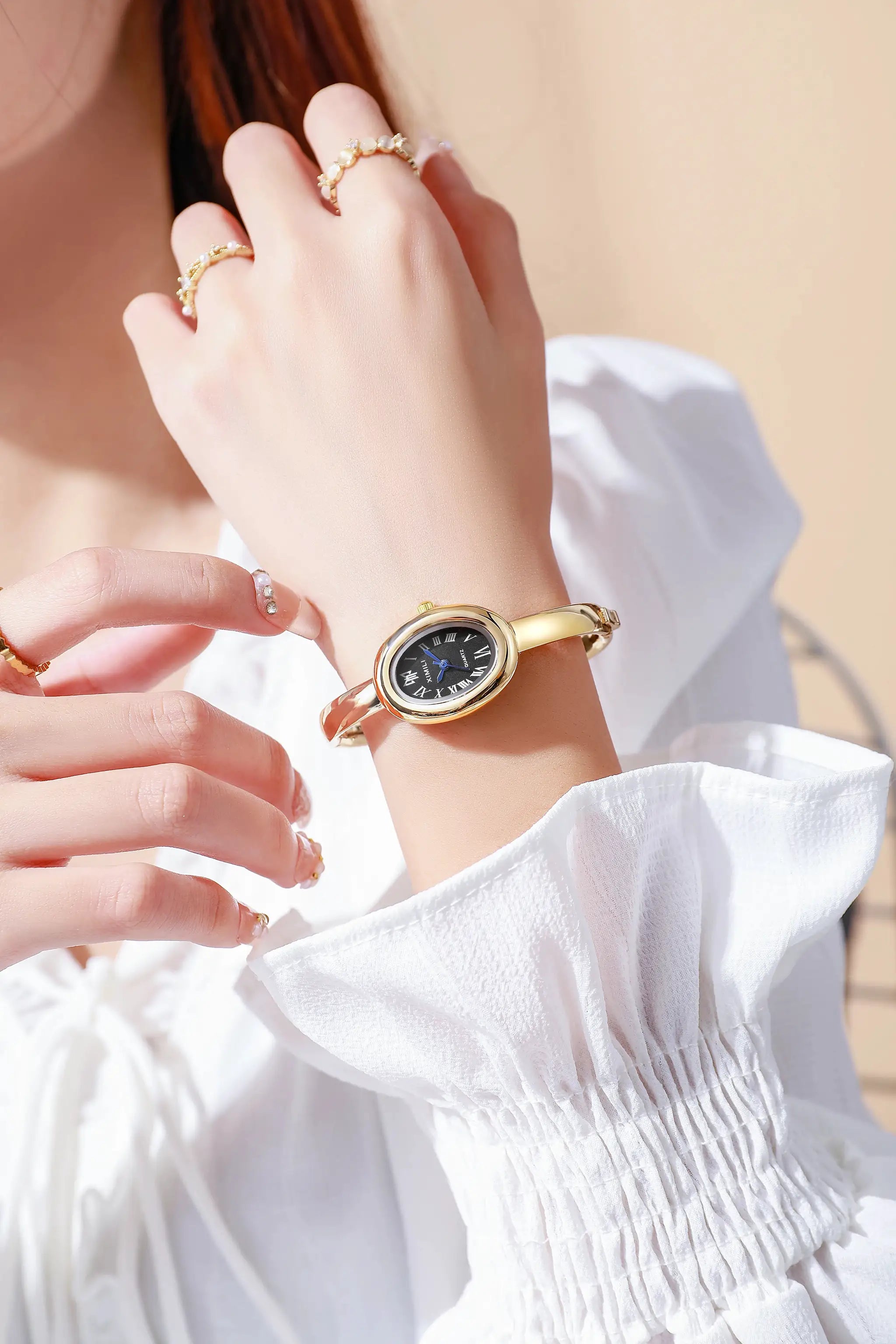 Gold-tone women's wristwatch with black Roman-numeral dial on a gold bracelet