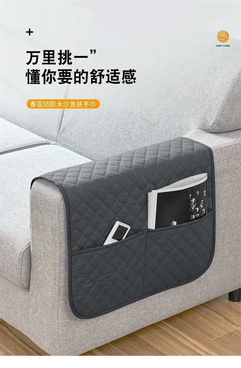 Quilted dark gray sofa armrest cover with front pockets for remote and phone storage; water-repellent.