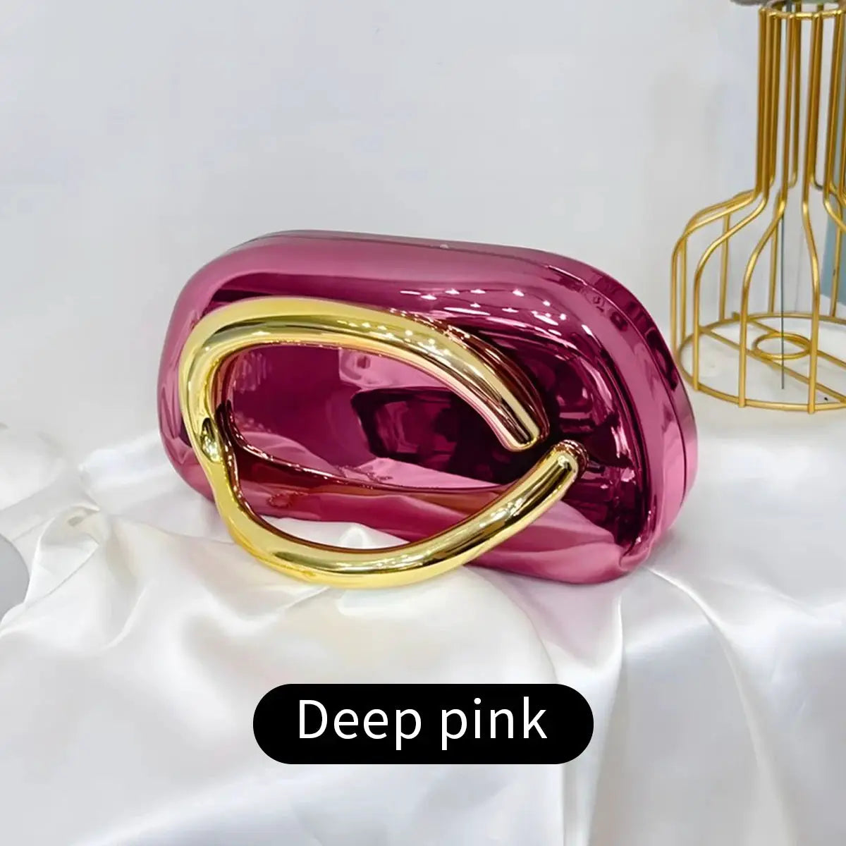 Acrylic box clutch bag in deep pink with a gold-tone curved handle.