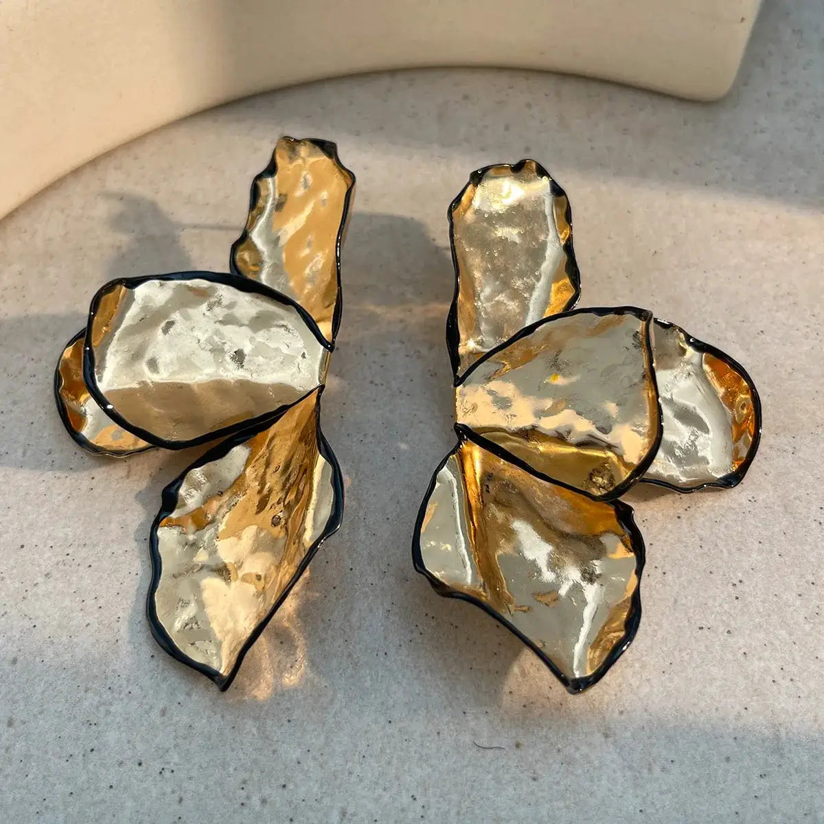 Pair of metal irregular pleated petal earrings; gold and silver-toned hammered petals with dark edges