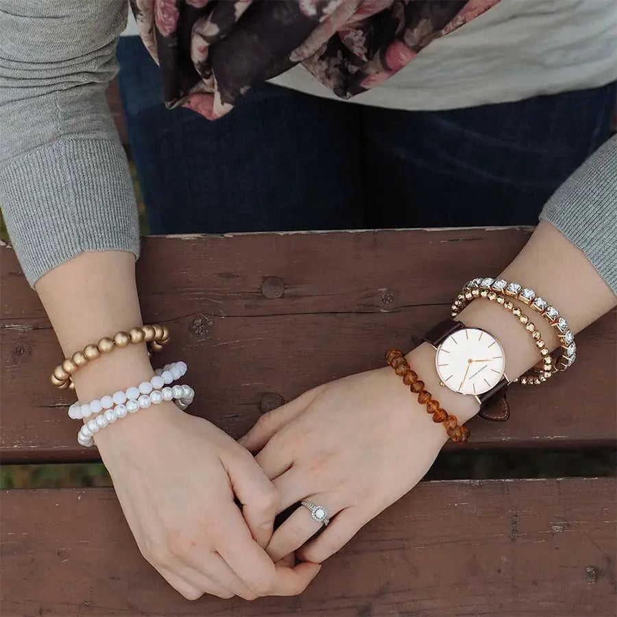 Women's 36mm rose-gold watch with brown leather strap and white dial, paired with amber bead bracelets
